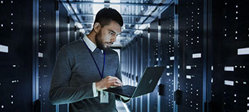 Person using a laptop while standing in a data center