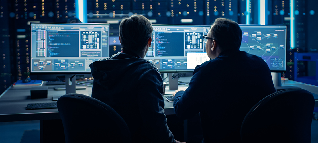 men in front of computer screens in a cyber lab