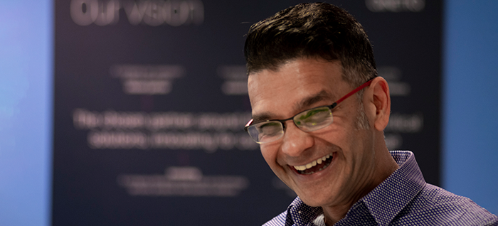 Smiling man in front of QinetiQ's Our Vision statement