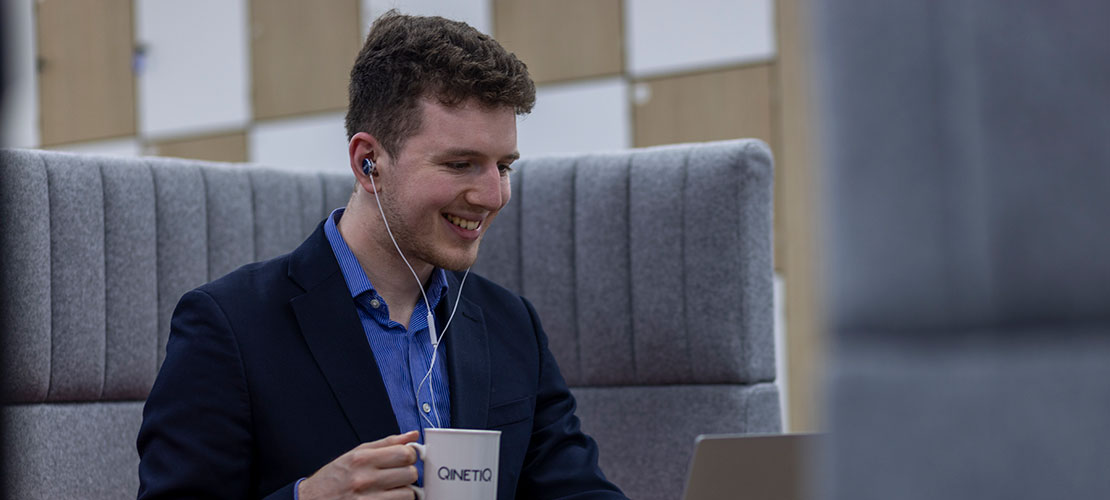 Graduate sitting at laptop with a hot drink