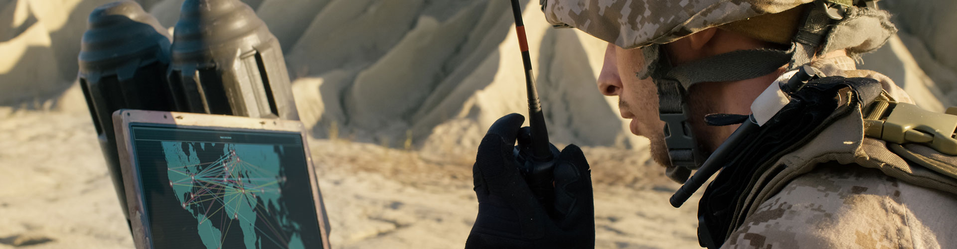 Soldier using laptop and radio for comms during military operation in the desert