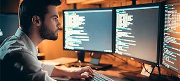 A man looking at multiple computer screens